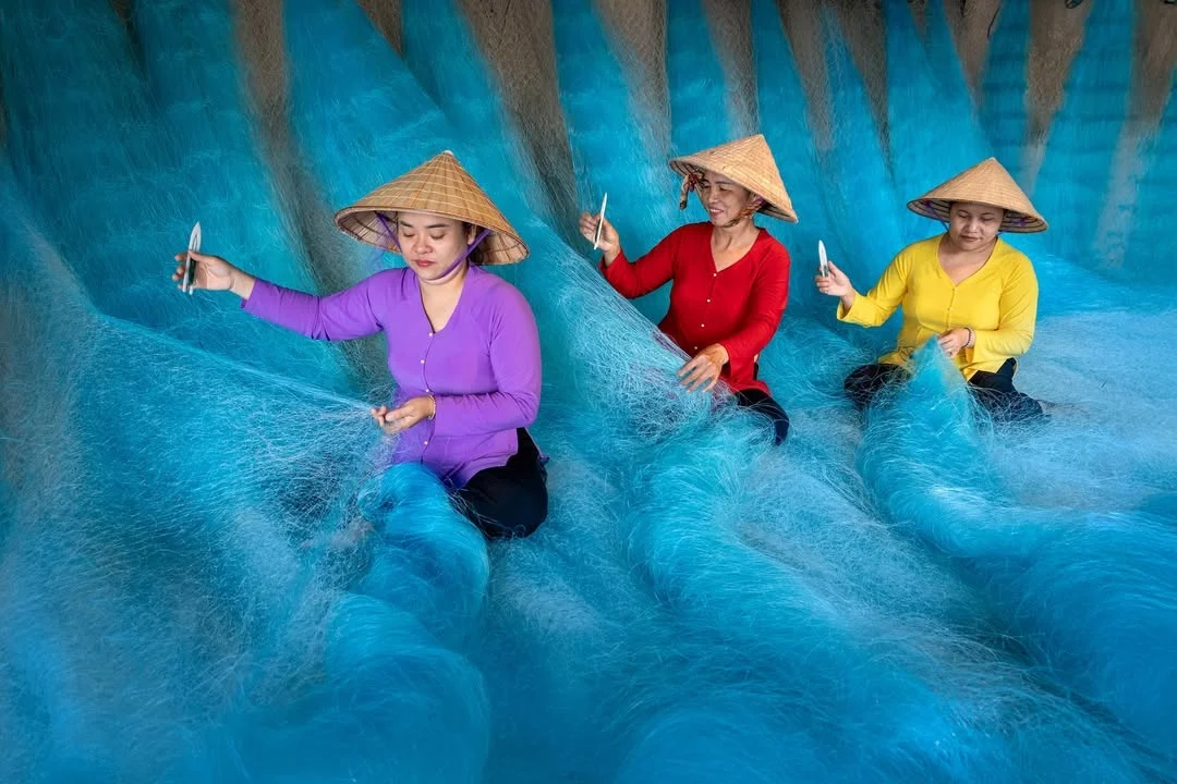 In Hoi An, women mend fishing nets.