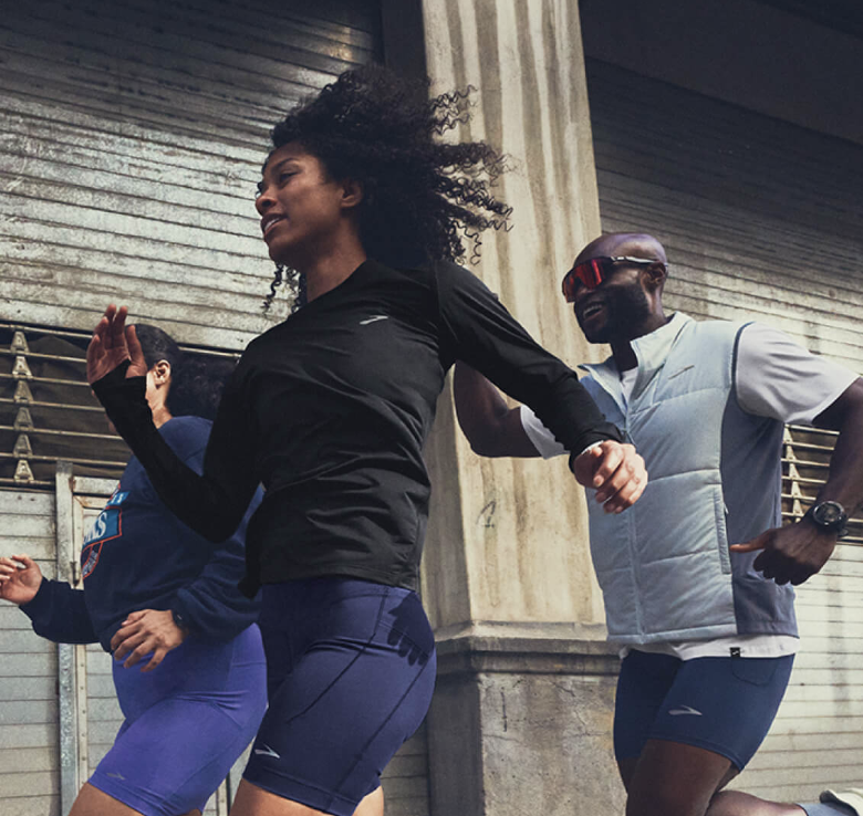 Brooks Run Club runners training together on a city street, representing the energy of race-day moments Brooks Run Club rewards