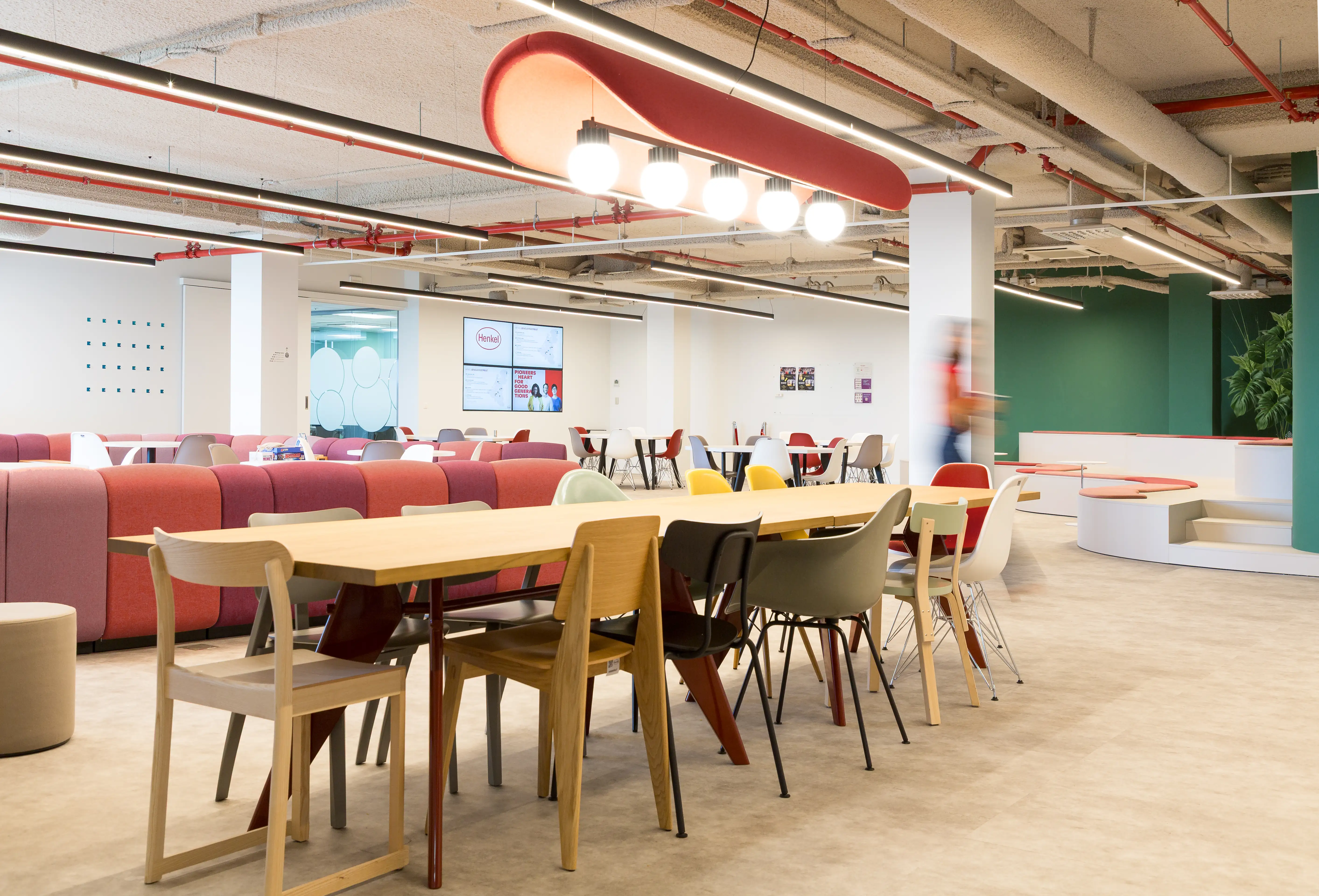 Cafétéria communautaire avec une grande table commune dans les bureaux de Henkel à Bruxelles, rénovée par Space Refinery
