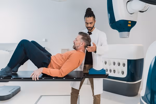 a person lying on a bed with another man standing behind him