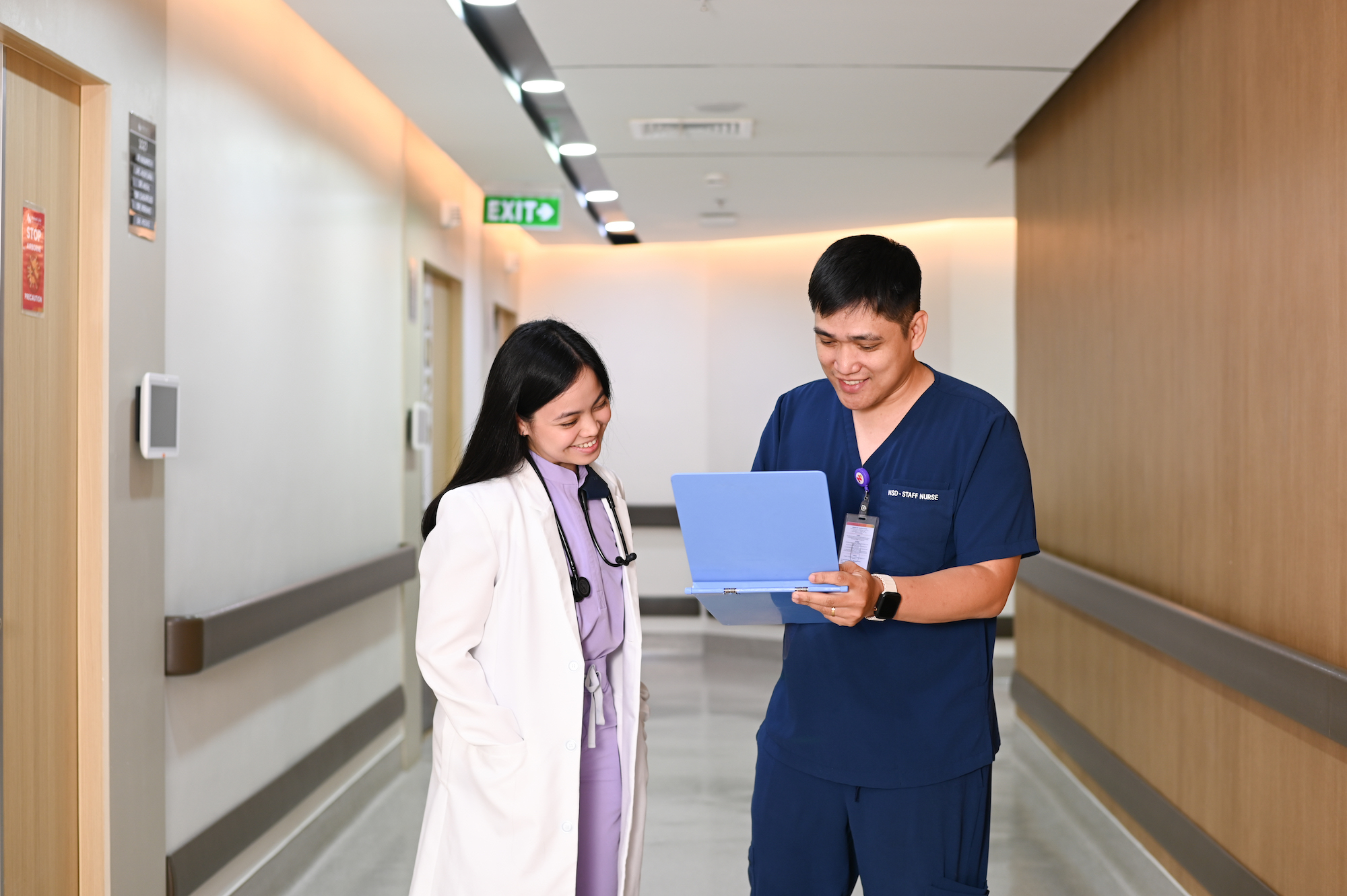 Doctor and nurse talking with a chart in hospital corridor