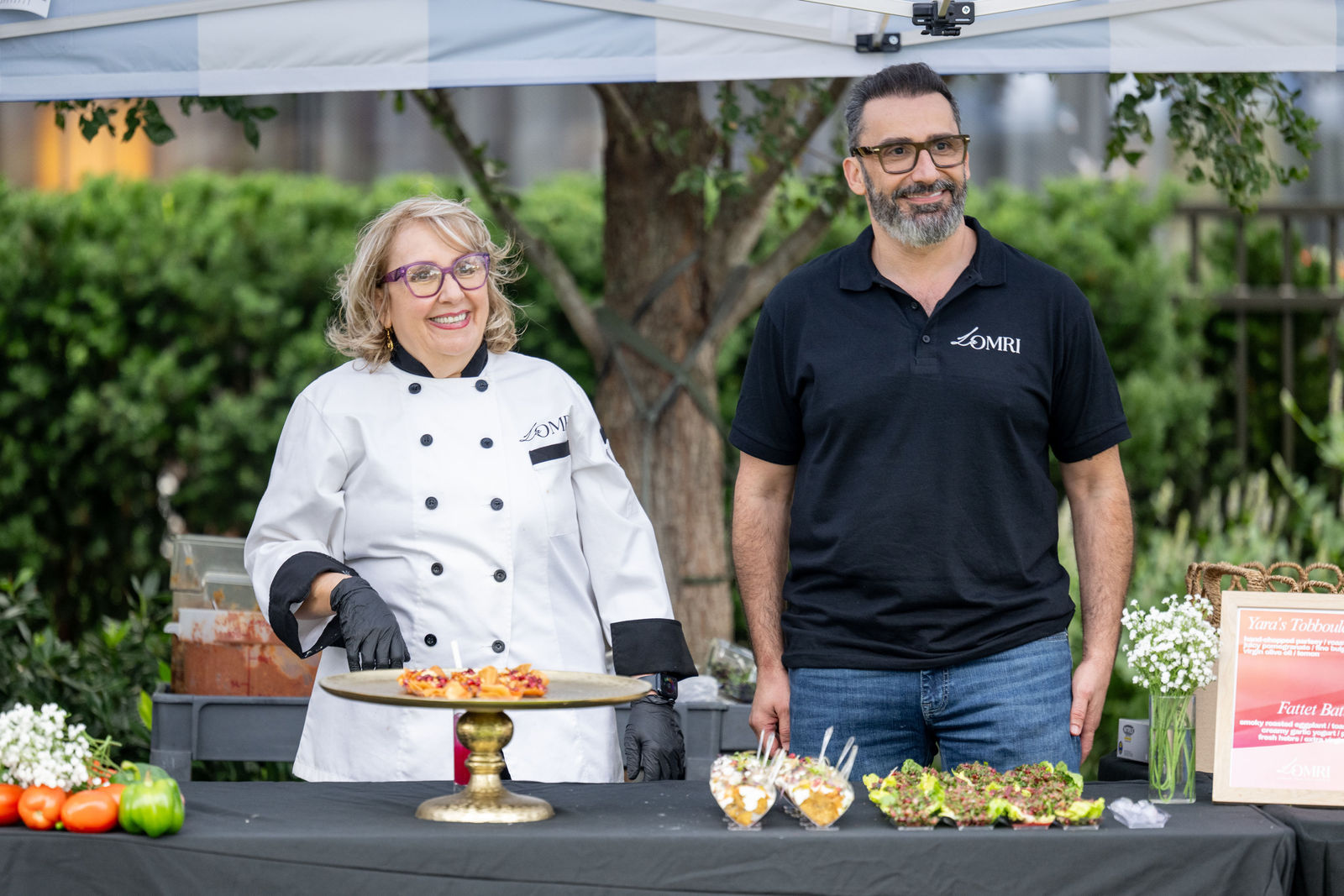 Chef Leila and a La Omri team member at their tasting booth presenting Mediterranean dishes at Capital One Center Culinary Week 2026