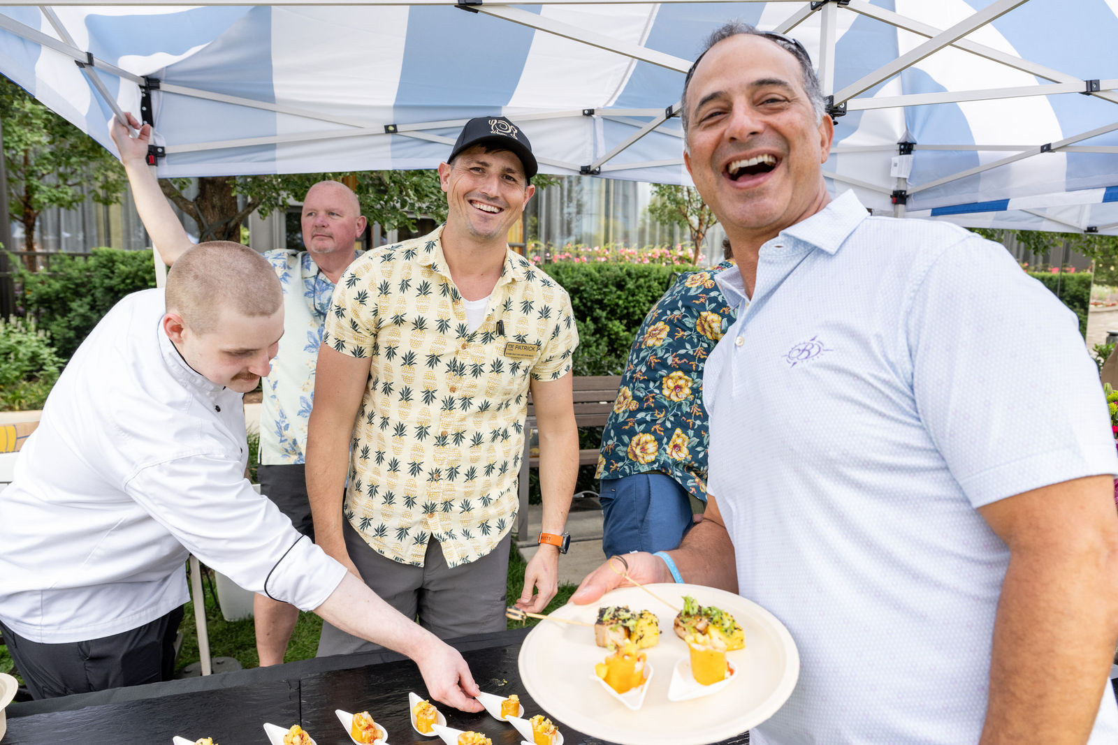 Chef and guests sharing a laugh over artisanal tasting bites at a vendor booth at Capital One Center Culinary Week 2026