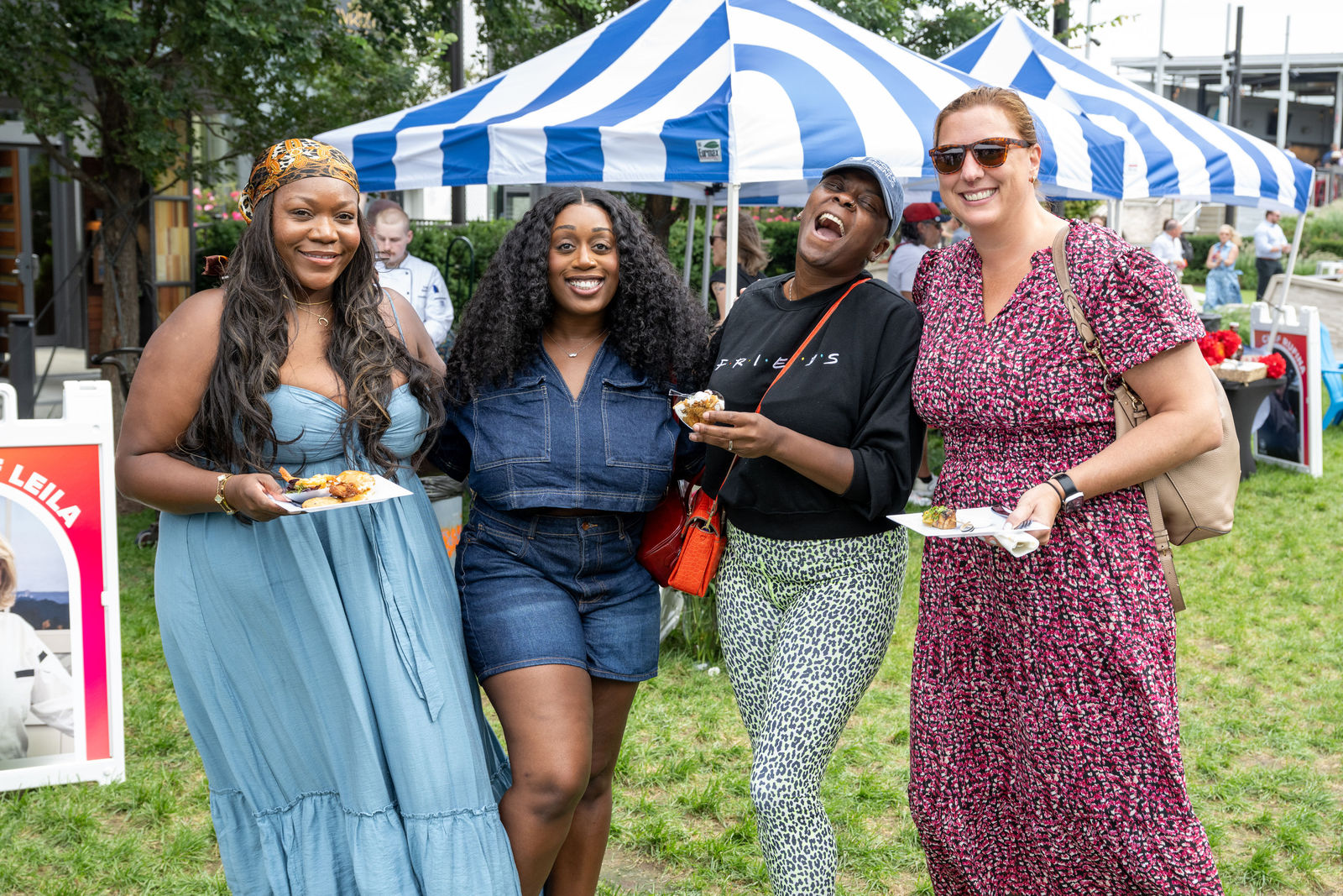 Four guests laughing together while holding plates of food at Capital One Center Culinary Week 2026