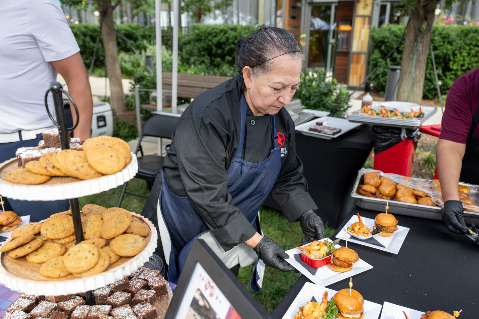 Chef plating sliders and shrimp dishes at an outdoor tasting station at Capital One Center Culinary Week 2026