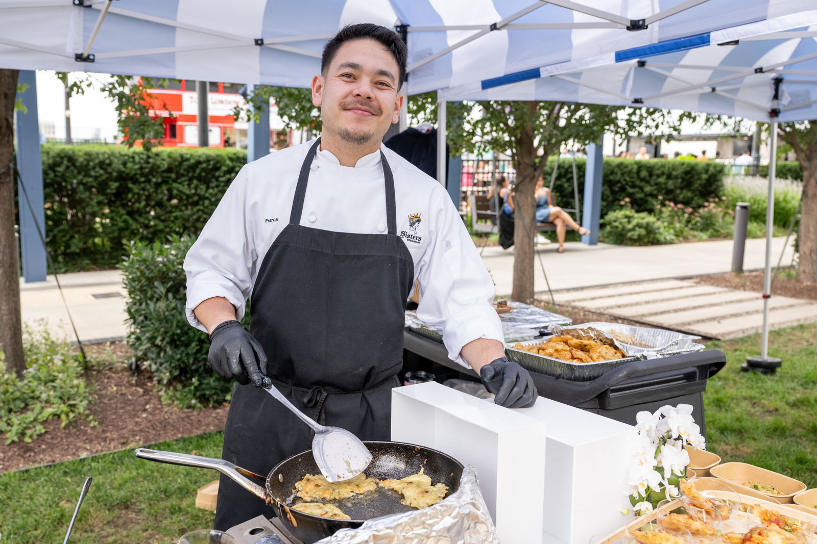 Chef cooking in a wok and smiling at an outdoor station at Capital One Center Culinary Week 2026