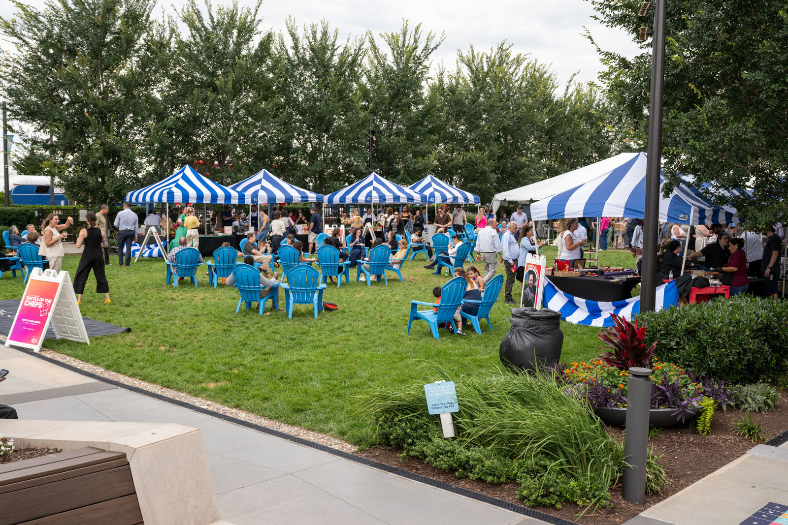 Guests seated and mingling on the lawn under blue-and-white striped tents at Capital One Center Culinary Week 2026