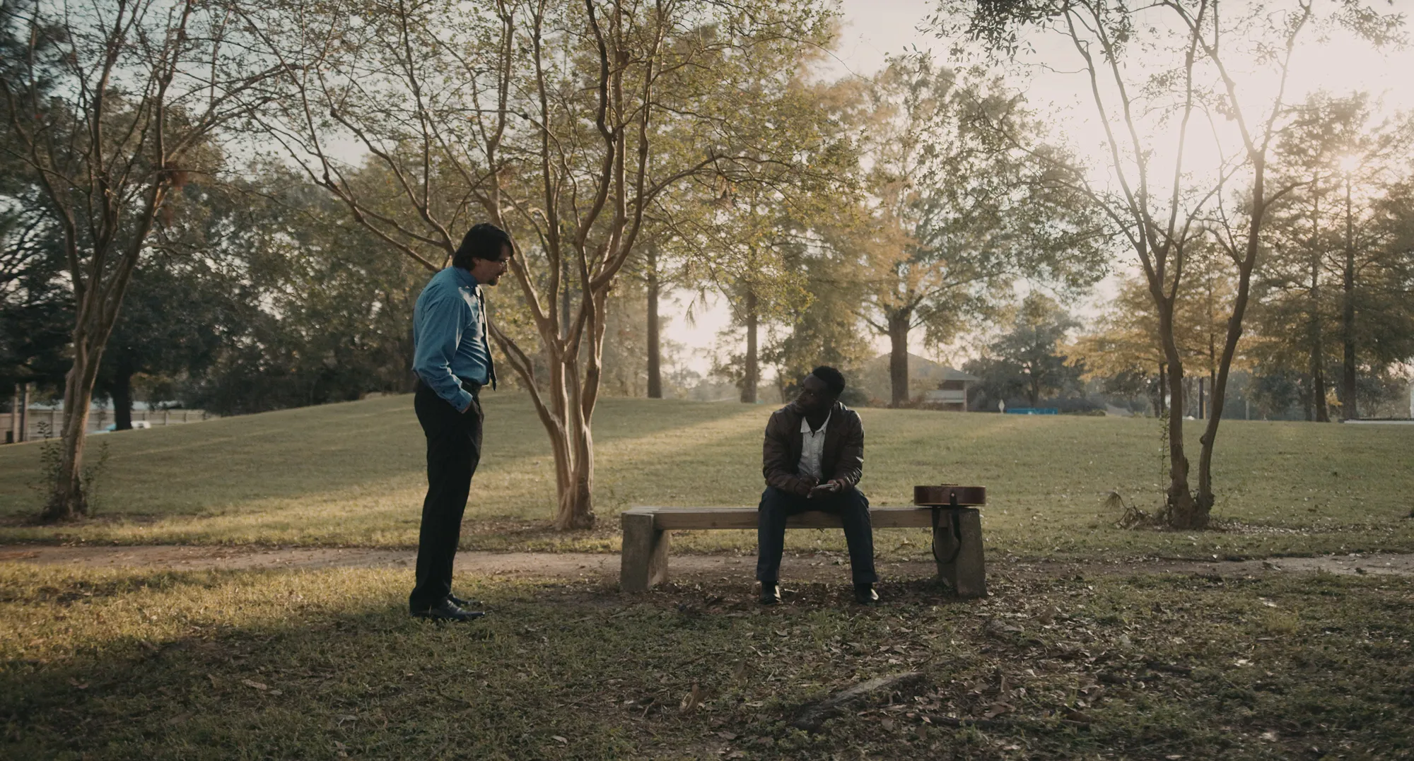17 year locust film still showing the young Haitian man Renee sitting in a park as a security guard approaches 