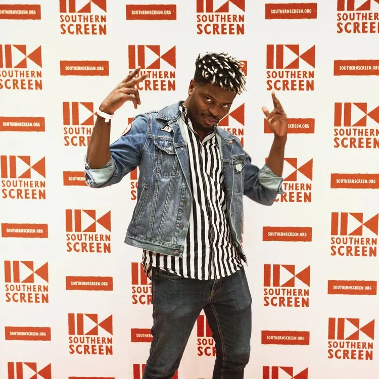 Southern Screen photo of attendee with wall of logos shown behind them