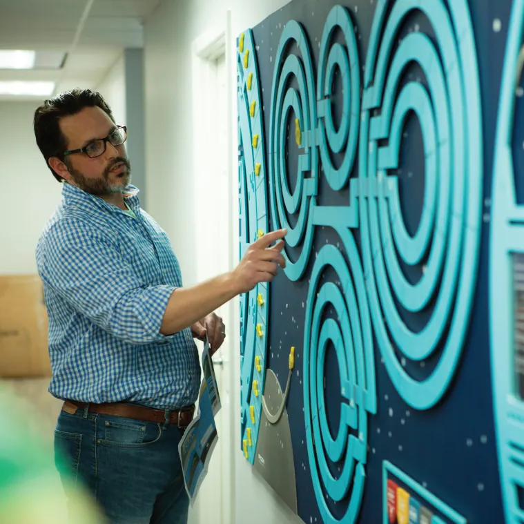 man pointing at sycon mission control game board