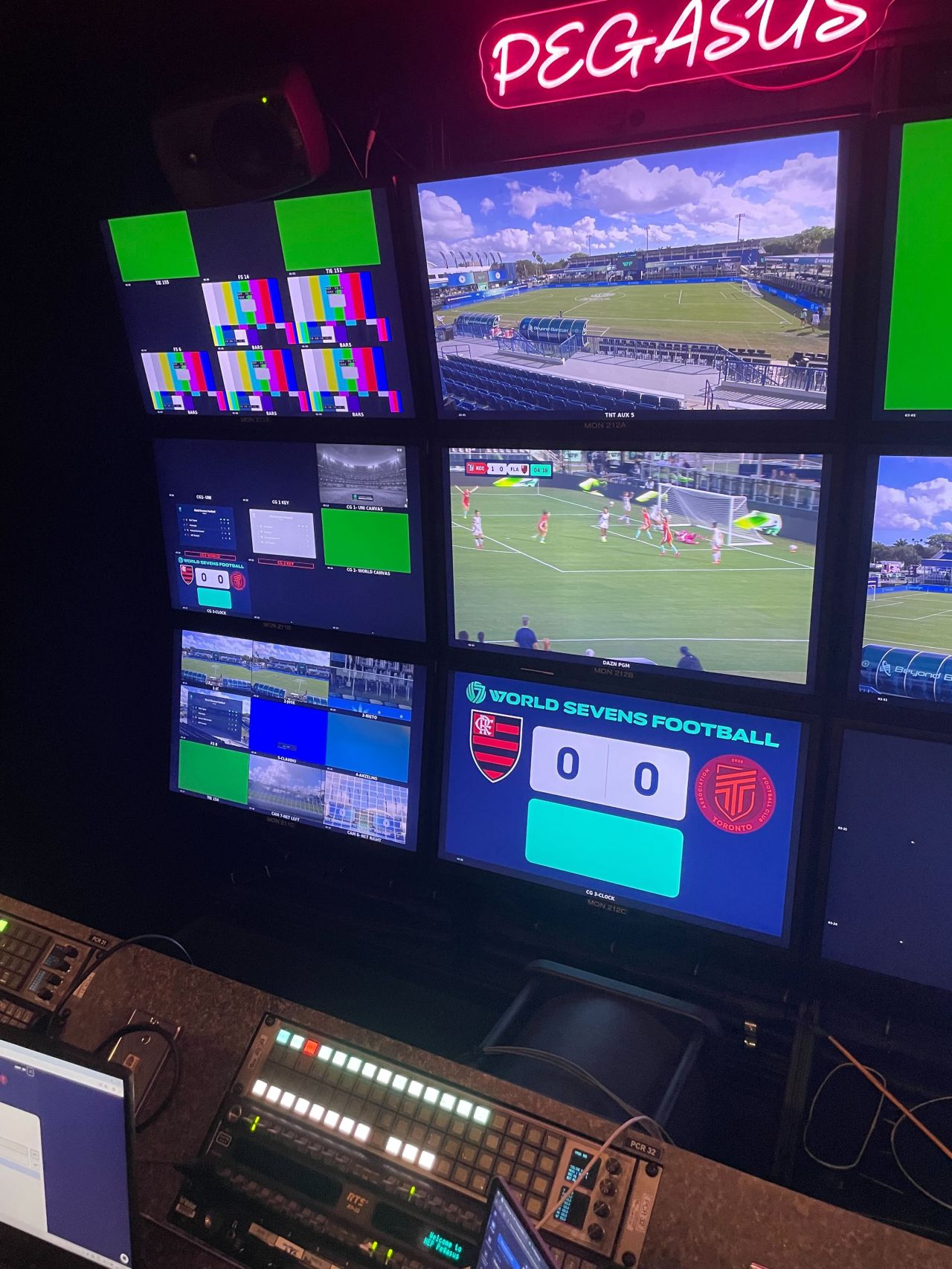 Broadcast monitors showing live match graphics and scorebug overlay