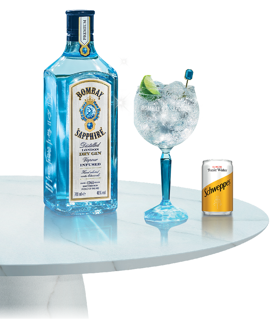 Bottle of Bombay Sapphire besides a glass and a Schweppes can on top of a marble table