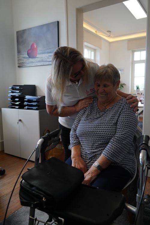 pflegepatientin wird von pflegerin an den Schultern gehoben und lächelt dabei