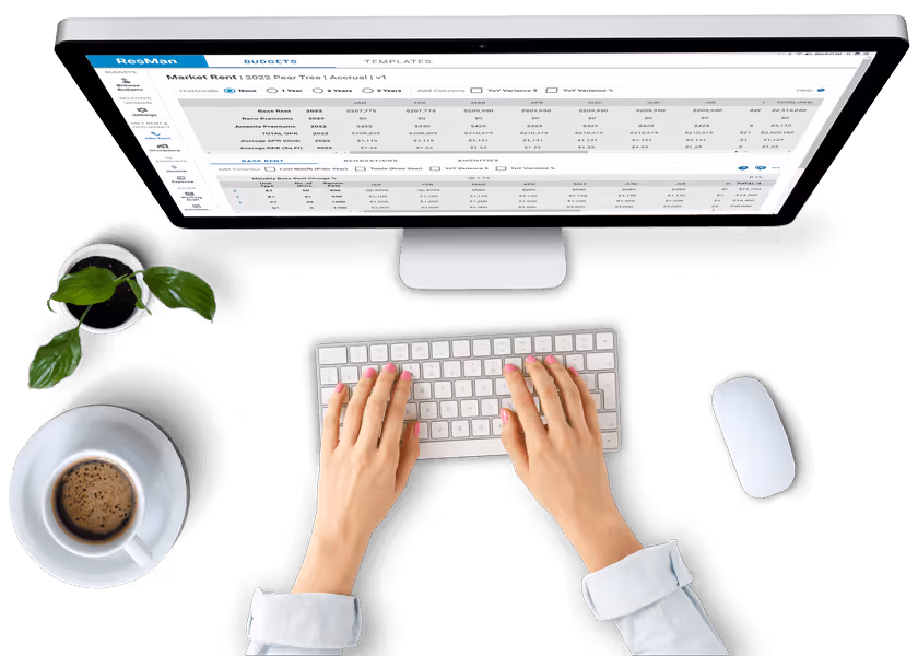 Overhead shot of hands typing in front of a desktop computer showing the ResMan Multifamily solution