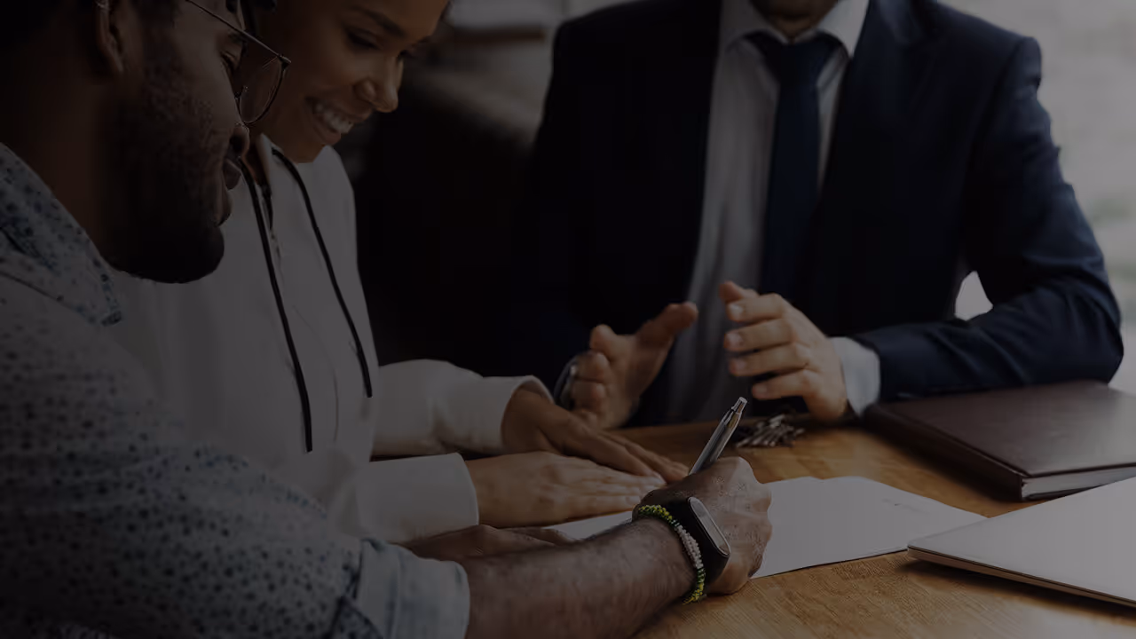 Two people signing a lease with a leasing agent.