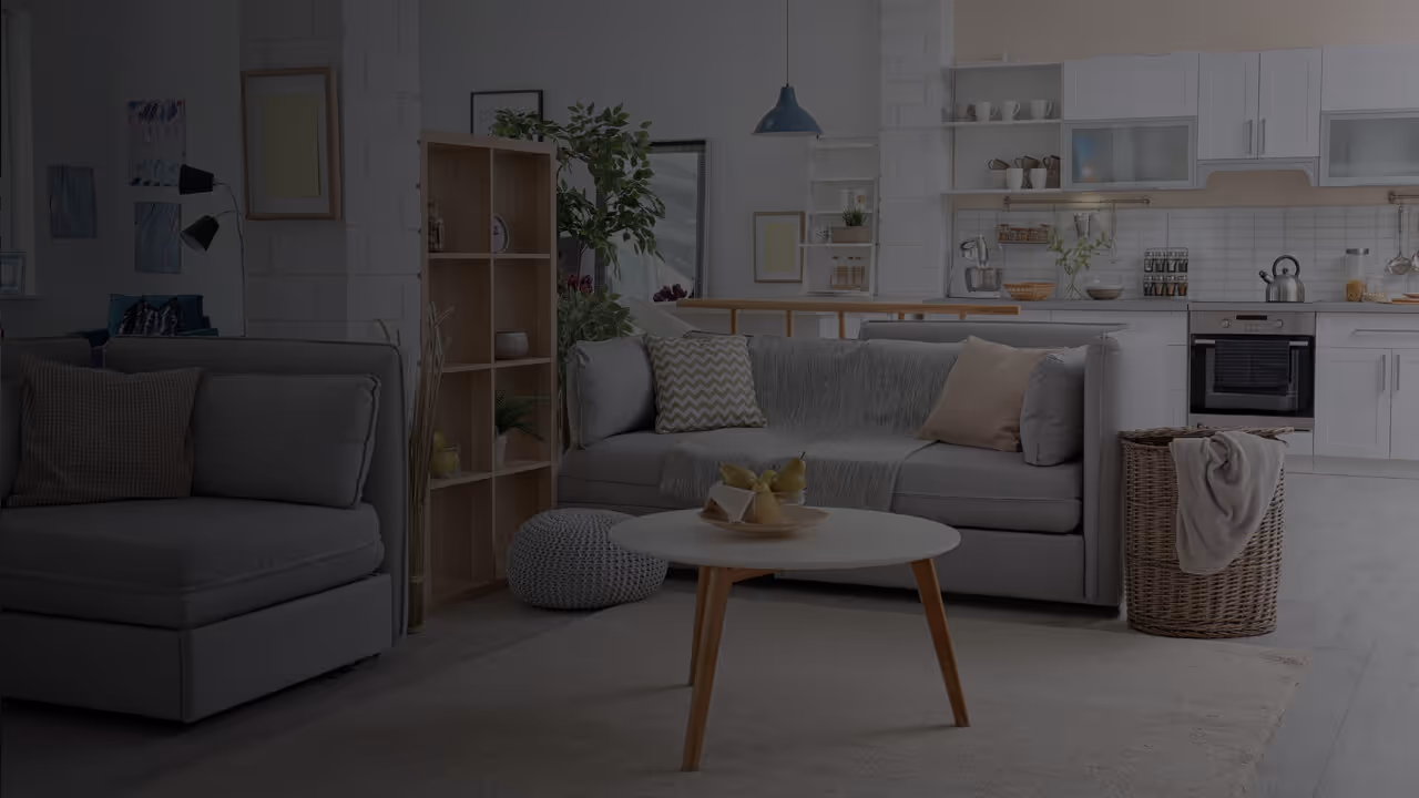 Interior of an apartment with a couch, a coffee table and a kitchen in the background.