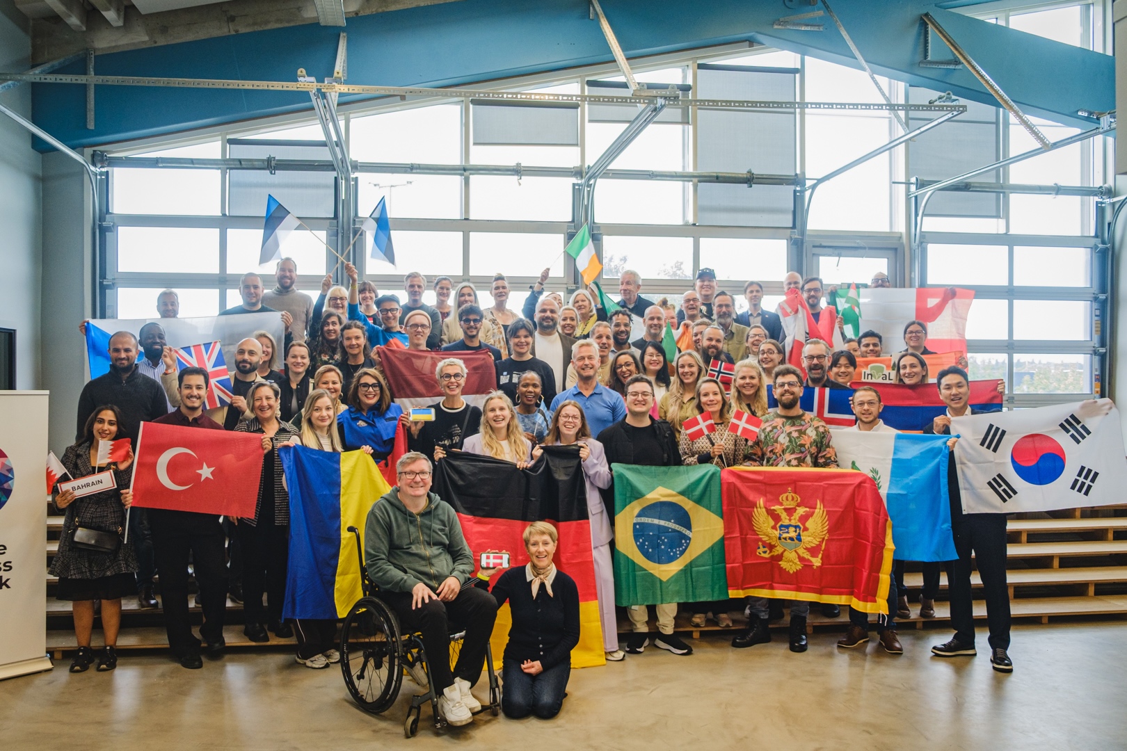 Representatives of the national winners from 25 countries across the world gather at BRIGHT 2025 for a photo moment holding the flags of their respective countries. 