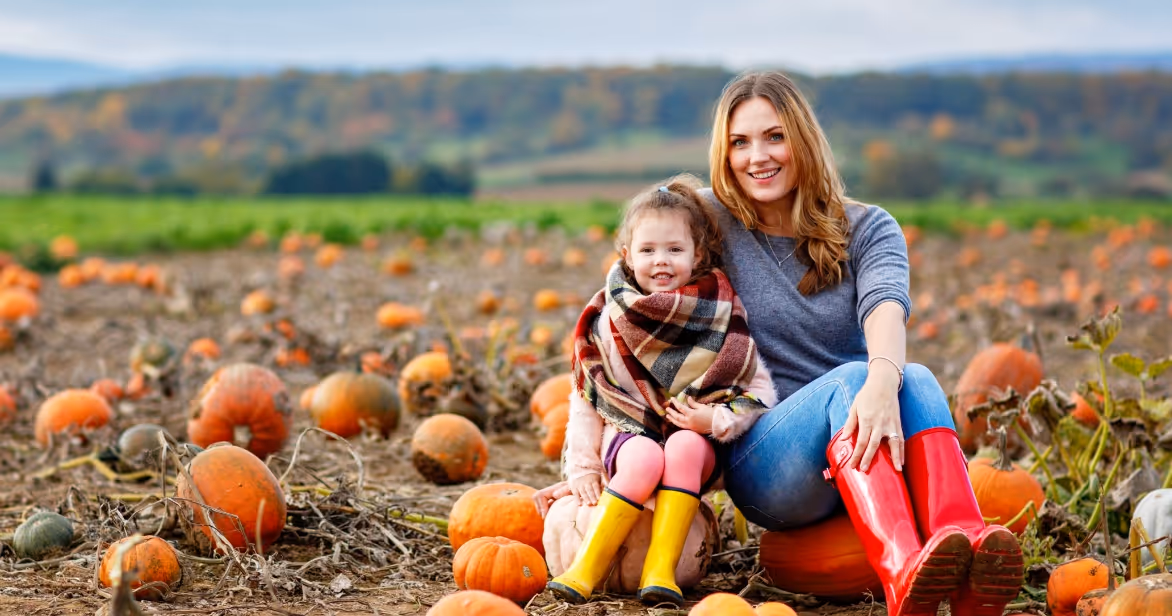 Mother and daughter in pumpkin patch in autumn, symbolising warmth, connection and foster care at Halloween