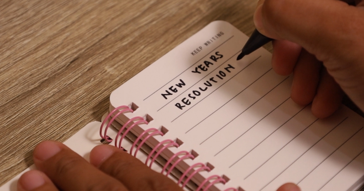a person writing new years resolution in a journal to represent that 2026 could be the year you explore fostering