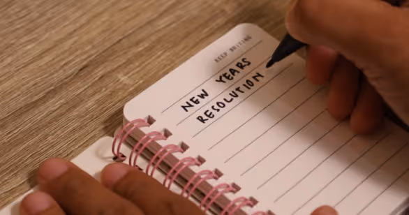 a person writing new years resolution in a journal to represent that 2026 could be the year you explore fostering