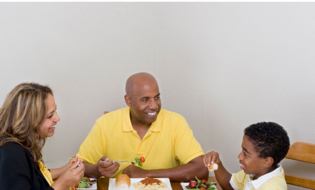 man and woman sitting at the dinner table with a child smiling 