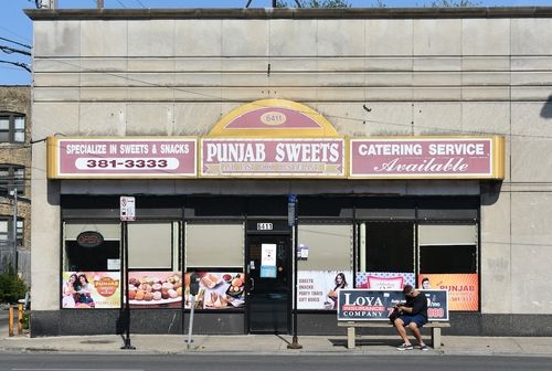 An image of plain building with a yellow and pink sign that reads, "Punjab Sweets".