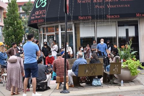 Image of a crowd of people gathered for an Aao Mil event on a street corner on Devon Avenue.