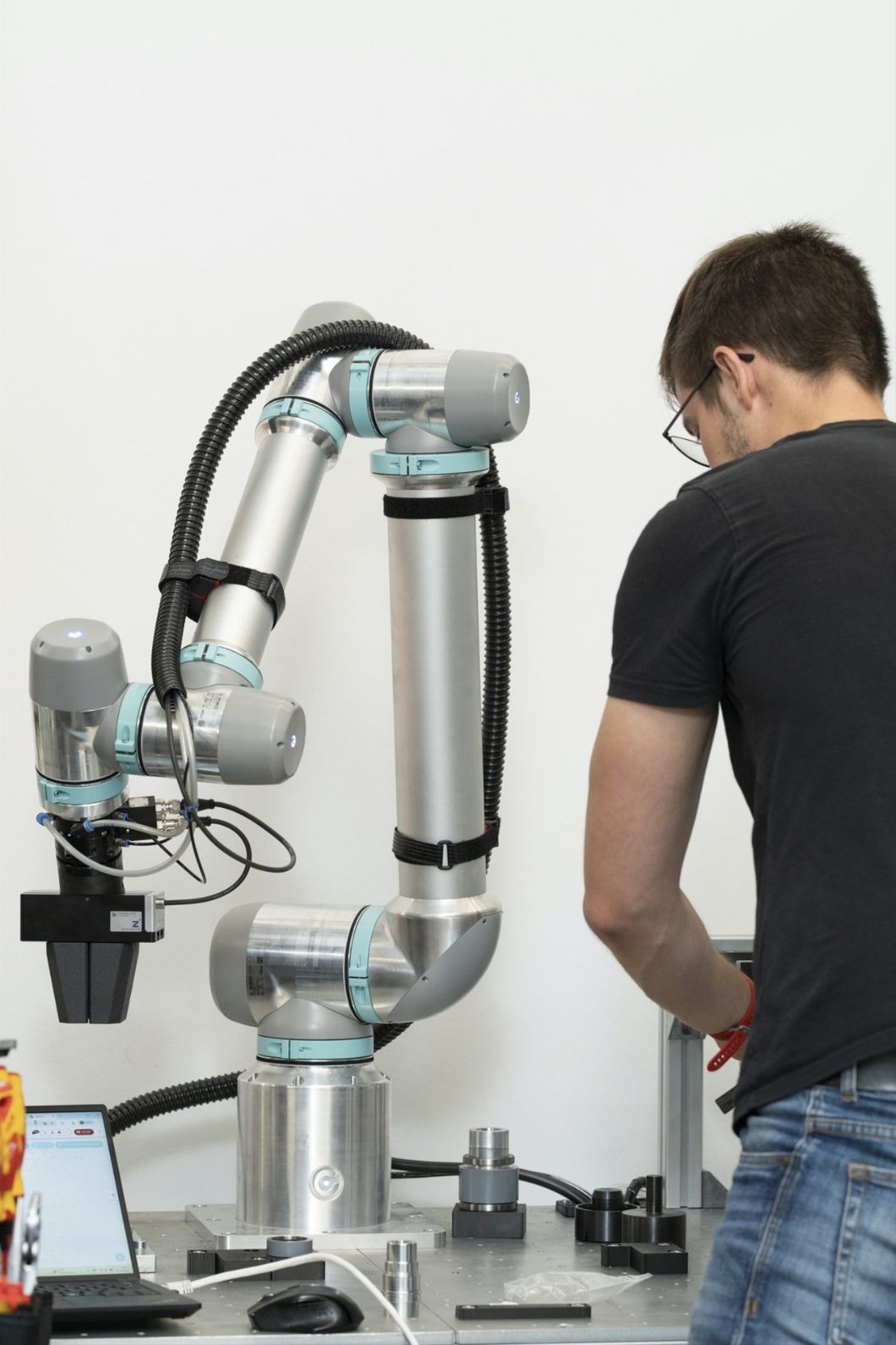 Ein Techniker arbeitet direkt neben einem Roboterarm und verdeutlicht den Unterschied im Cobot vs. Robot Vergleich, bei dem Cobots für die sichere Zusammenarbeit mit Menschen ausgelegt sind.
