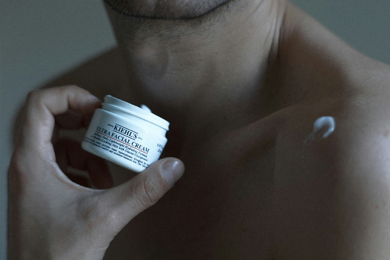 Close up of man with no shirt holding a face cream