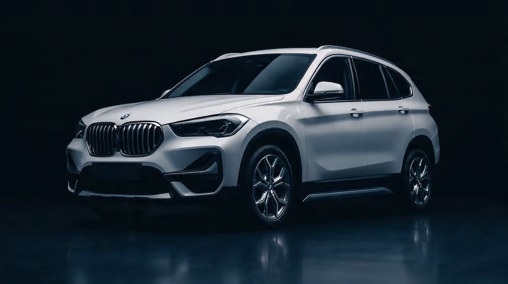 Un SUV BMW argintiu, cu un design elegant și jante strălucitoare, pe un fundal întunecat.