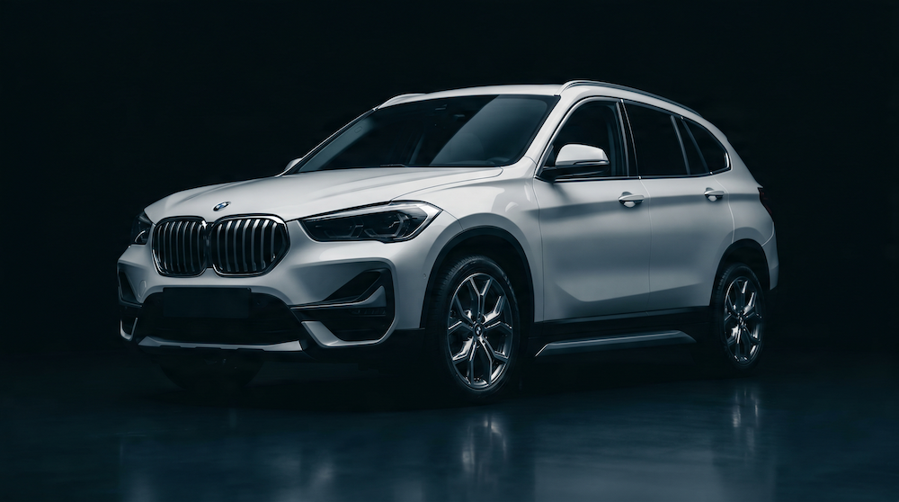 A silver BMW SUV with a sleek design and shiny rims against a dark background.