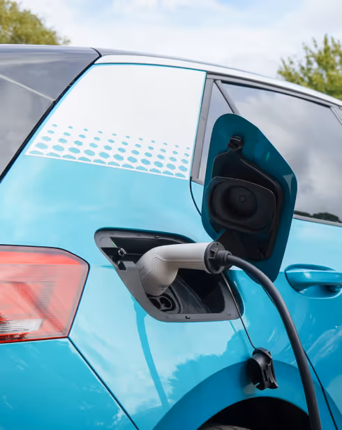 A light blue battery electric vehicle being charged.