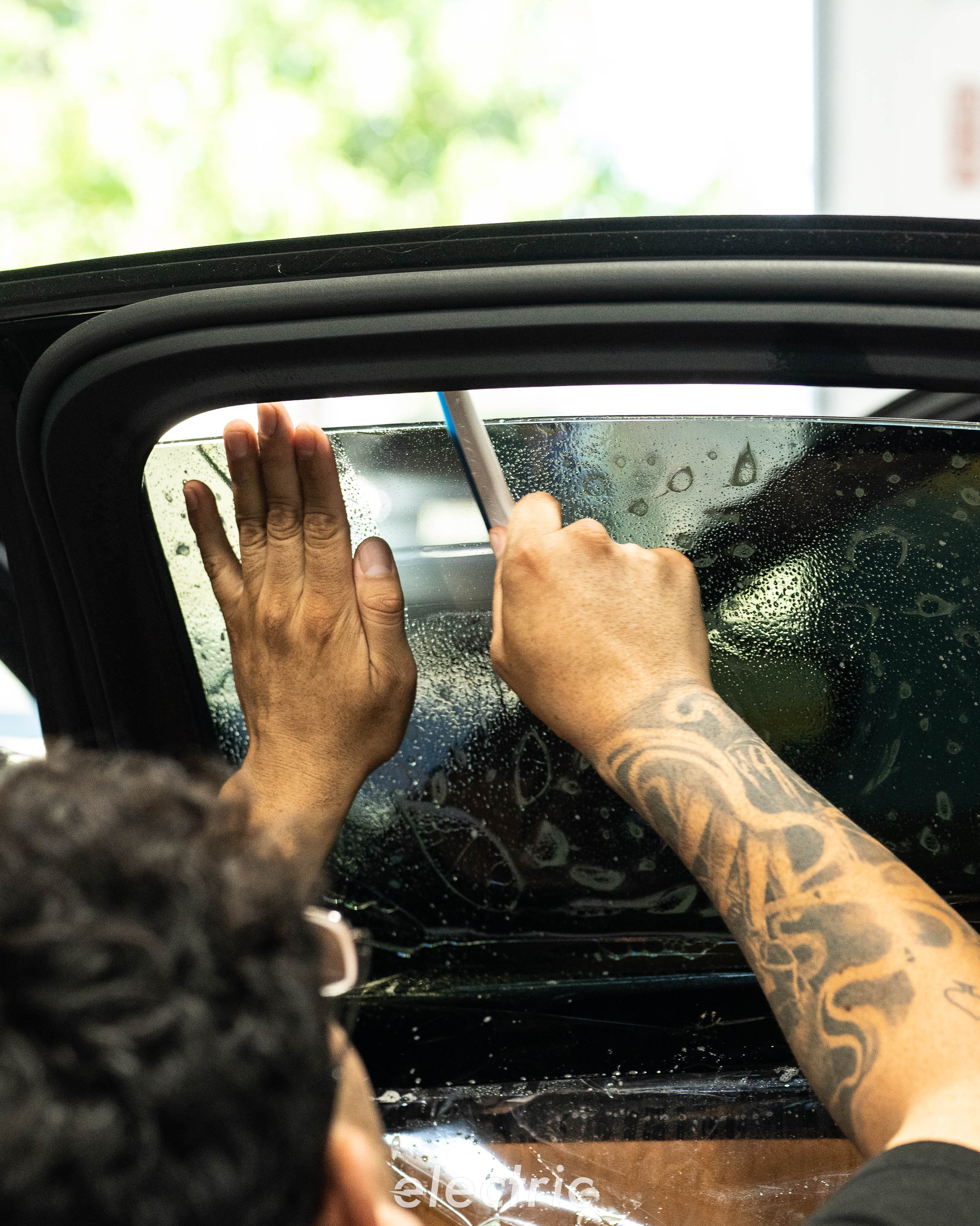 Technician installing ceramic window tint on a BMW M340i