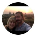 Woman with curly light brown hair, wearing a gray scarf, looking at the camera with a neutral expression.