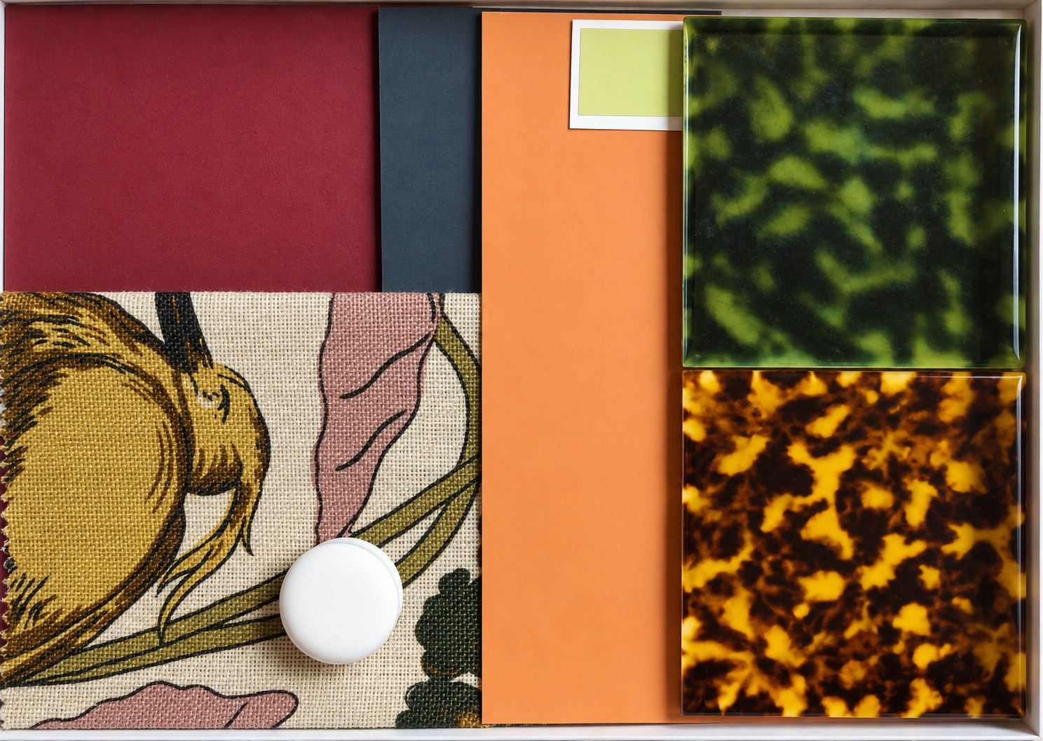 Samples in a tray: oxblood, charcoal and terracotta, a botanical linen and tortoiseshell tiles