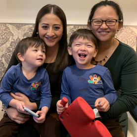 A host mom with her two kids and au pair sitting on the couch.