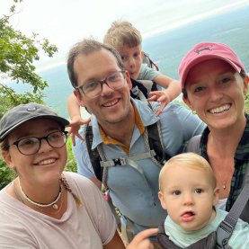 A family of four on a hike taking a picture with their au pair.