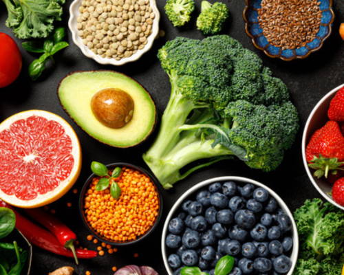 A variety of fruits, vegetables, nuts, and grains laid out on a black table.