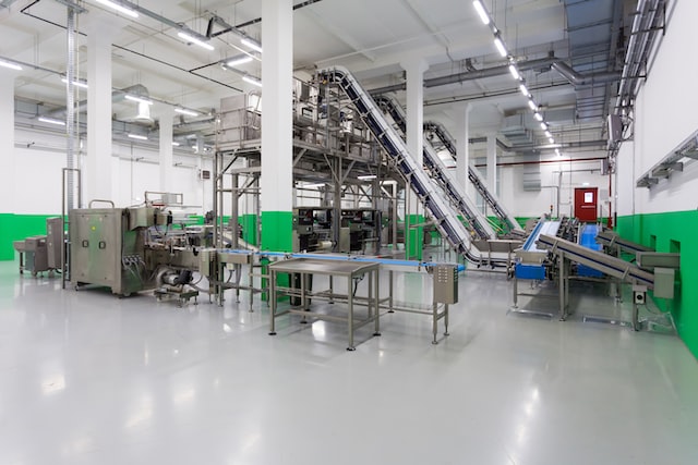 Clean, modern industrial facility with stainless steel machinery and conveyor belts on a polished epoxy floor.