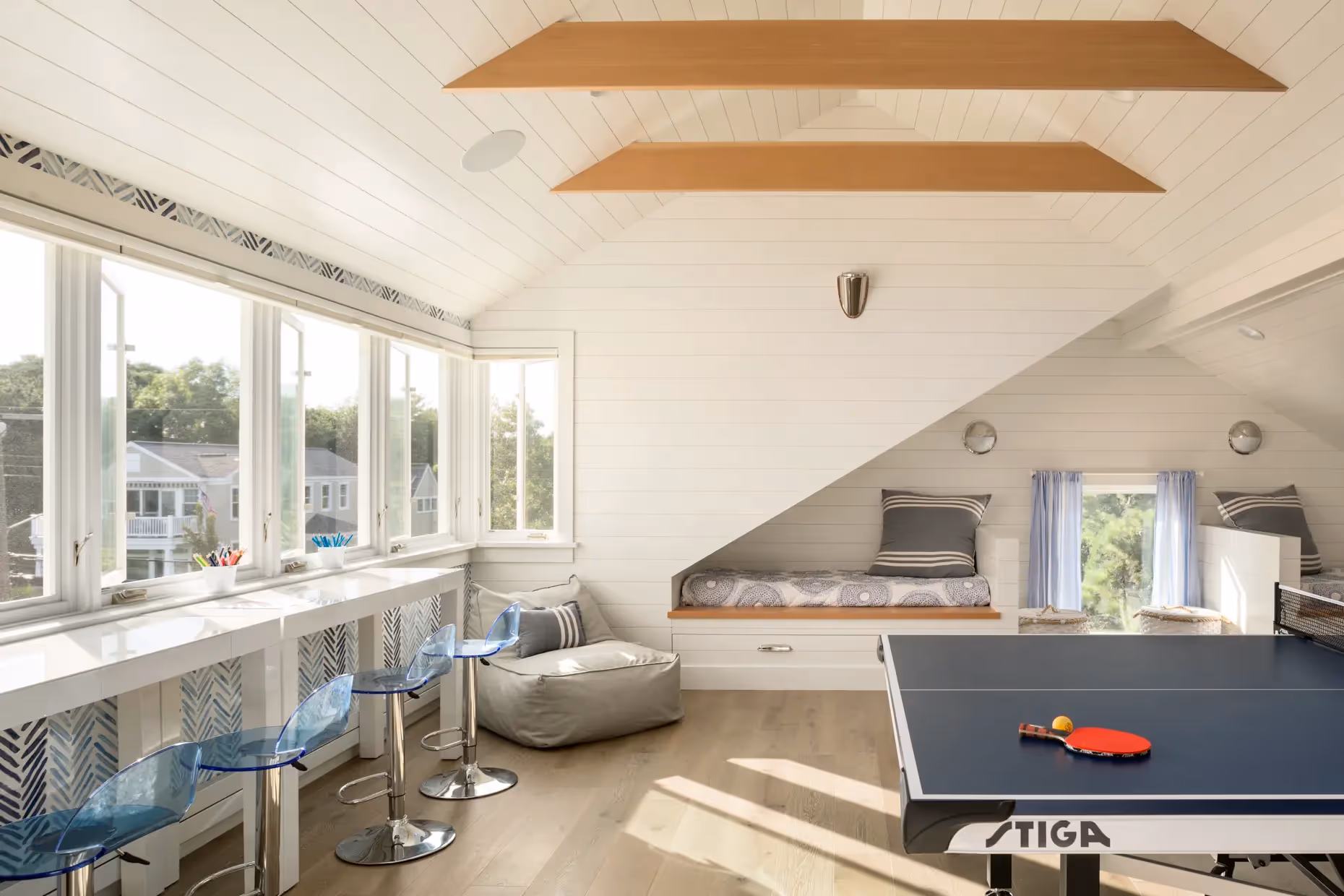 Bright attic room with ping pong table, desk, bed, and large windows