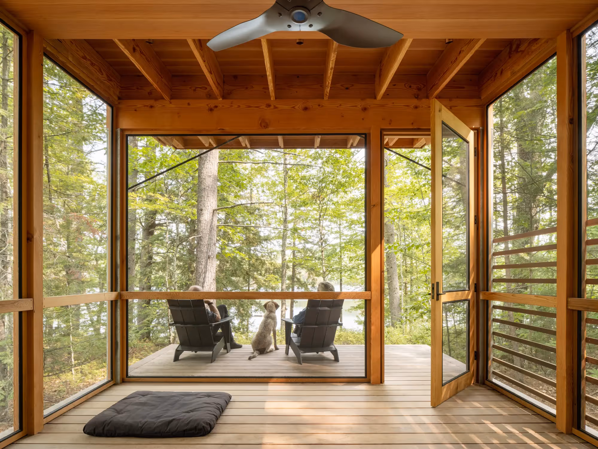 Dog and two chairs on screened porch overlooking peaceful forest