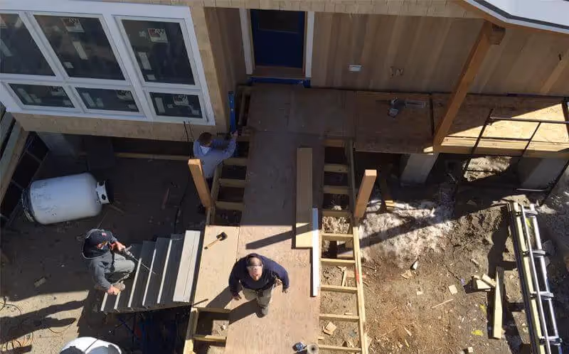 Construction workers building wooden deck and stairs from overhead view