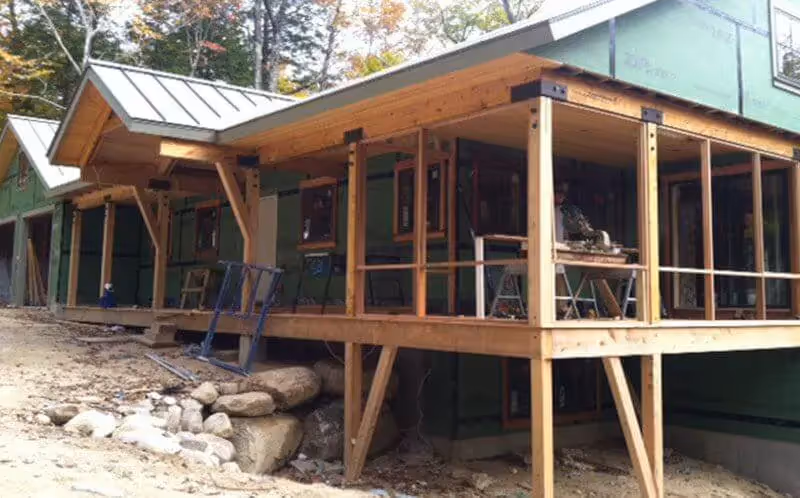 Wooden cabin on stilts under construction with green siding
