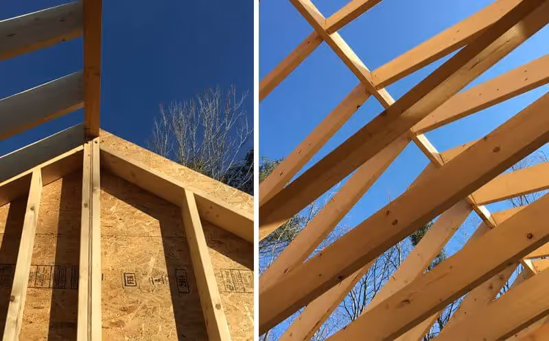 Wooden roof framing in progress with structural beams against blue sky