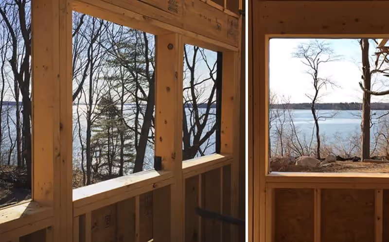 Wooden framed windows overlooking bare trees and a lake in winter