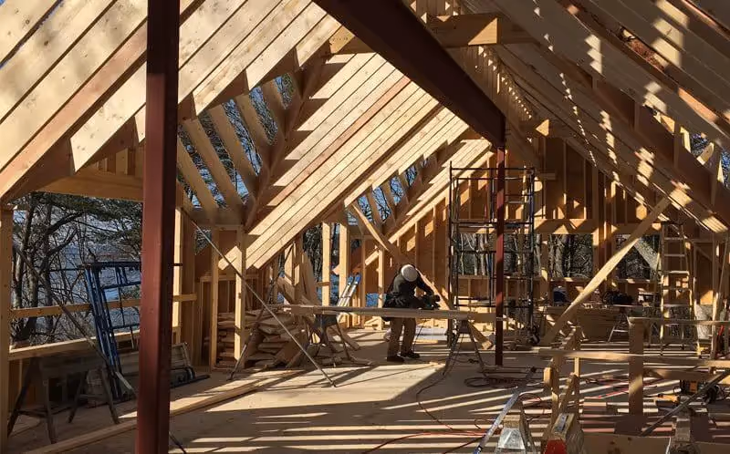 Wooden roof framing with sunlight casting shadows during house construction