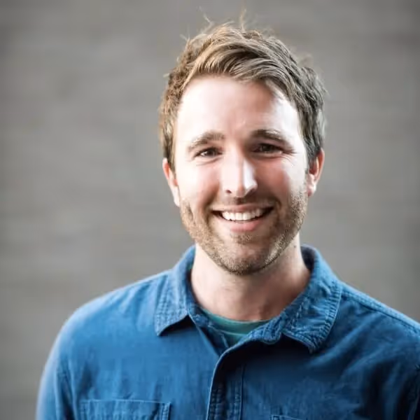 Smiling person in blue shirt against gray background
