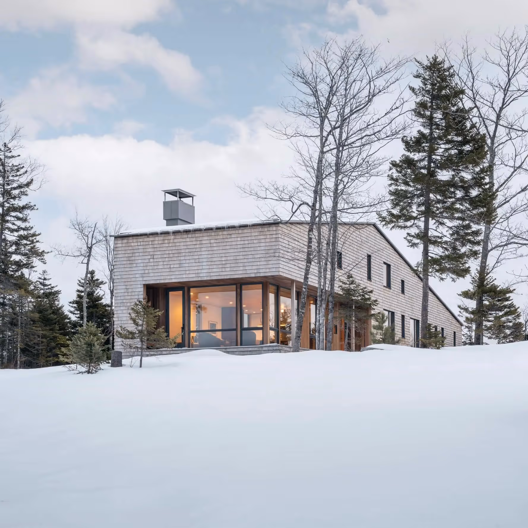 Modern wooden house with large windows nestled in snowy winter landscape