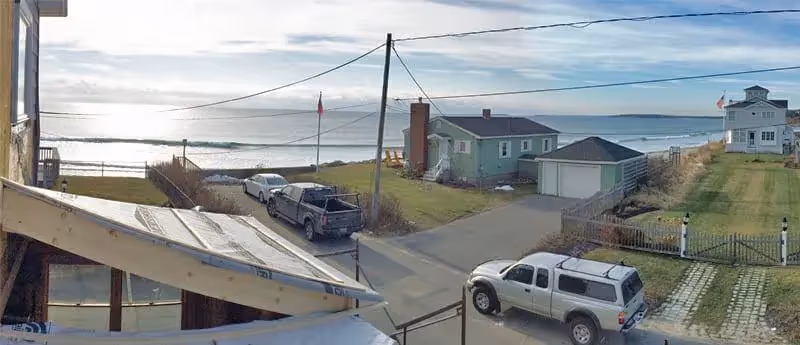Coastal neighborhood with pickup trucks, beach view, and utility lines
