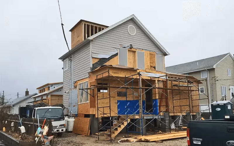House under construction with scaffolding and wooden panels